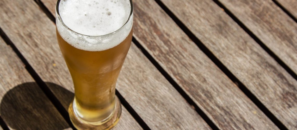 A glass of cold beer on a wooden surface on a sunny day