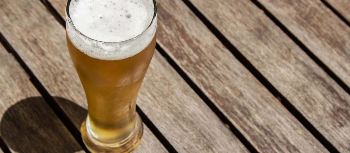 A glass of cold beer on a wooden surface on a sunny day